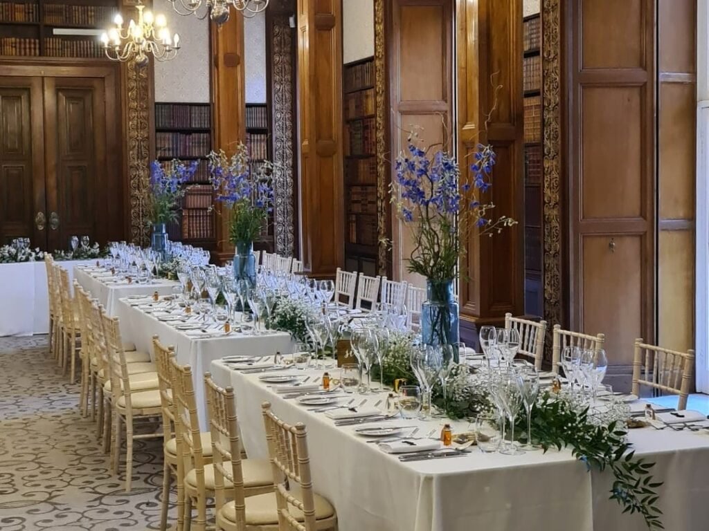Luxury wedding tablescape with blue floral arrangements in an elegant wood-panelled venue.
